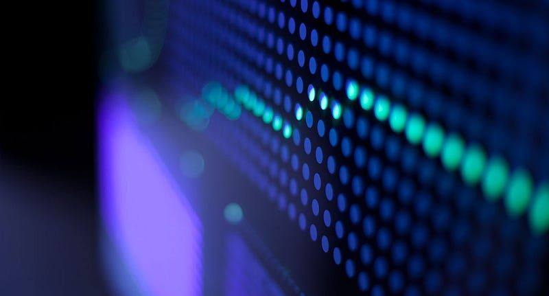 A close photograph of a blue and green LED array with a very shallow depth of field, the lights receding into soft bokeh.
